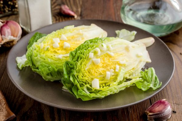 Lettuce buds cut in salad with oil and garlic, on rustic wood
